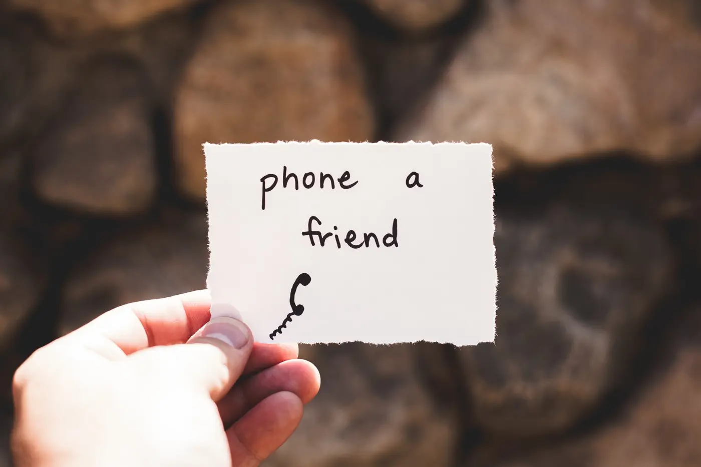 Un biglietto con scritto phone a friend: chiedere aiuto per smettere di fumare