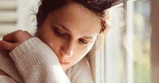 Una donna pensierosa alla finestra durante un periodo di depressione
